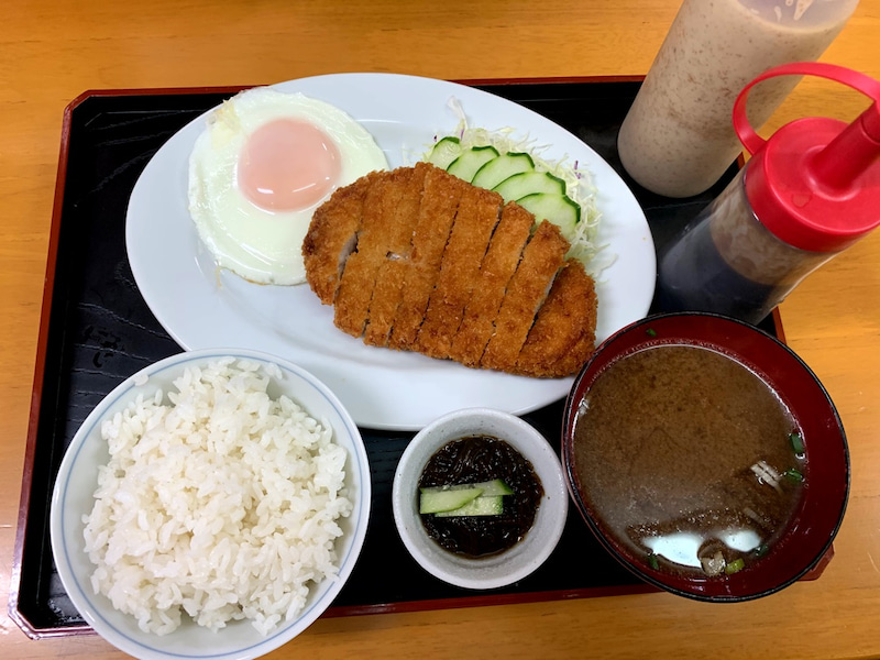 ひがし食堂のとんかつ定食。黄金色に揚げられたカツとキャベツ、ご飯、スープがセット