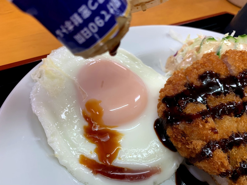 定食の卵に醤油をかける様子
