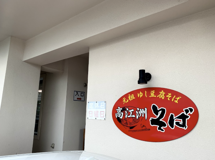 高江洲そばの店舗入口。赤い大きな楕円形の看板が目印