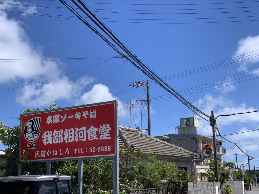 青空の下に立つ、大きな看板が目印の我部祖河食堂本店の外観
