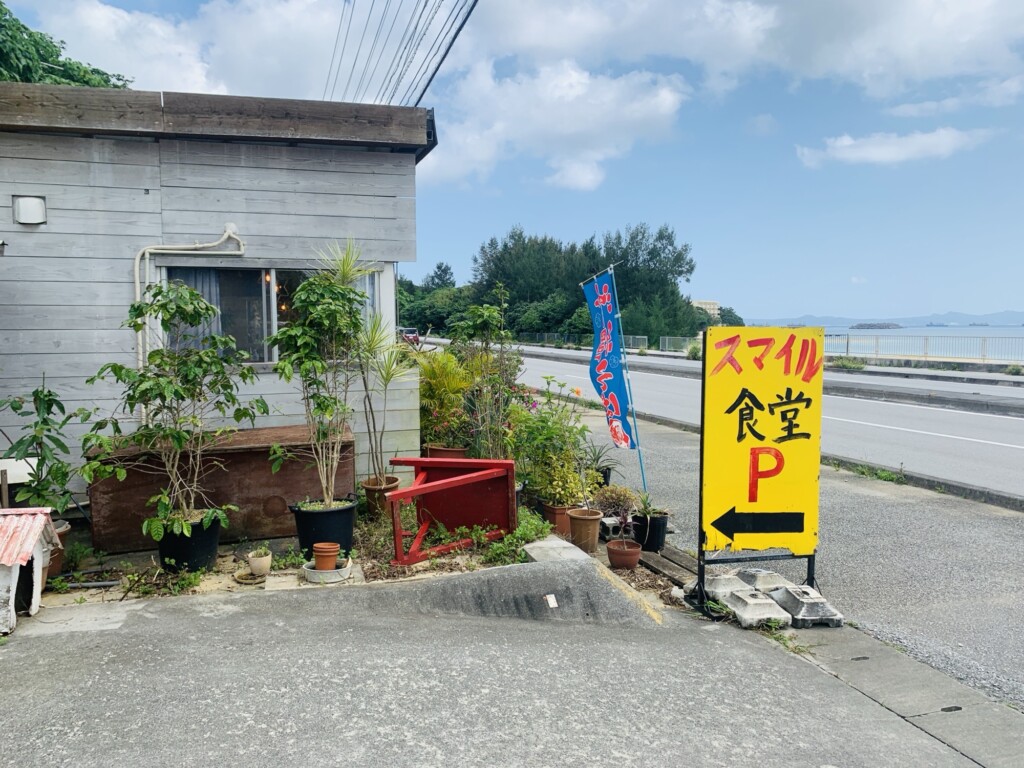 スマイル食堂＆Cafeの駐車場案内看板と店舗外観。入口の広さを確認。