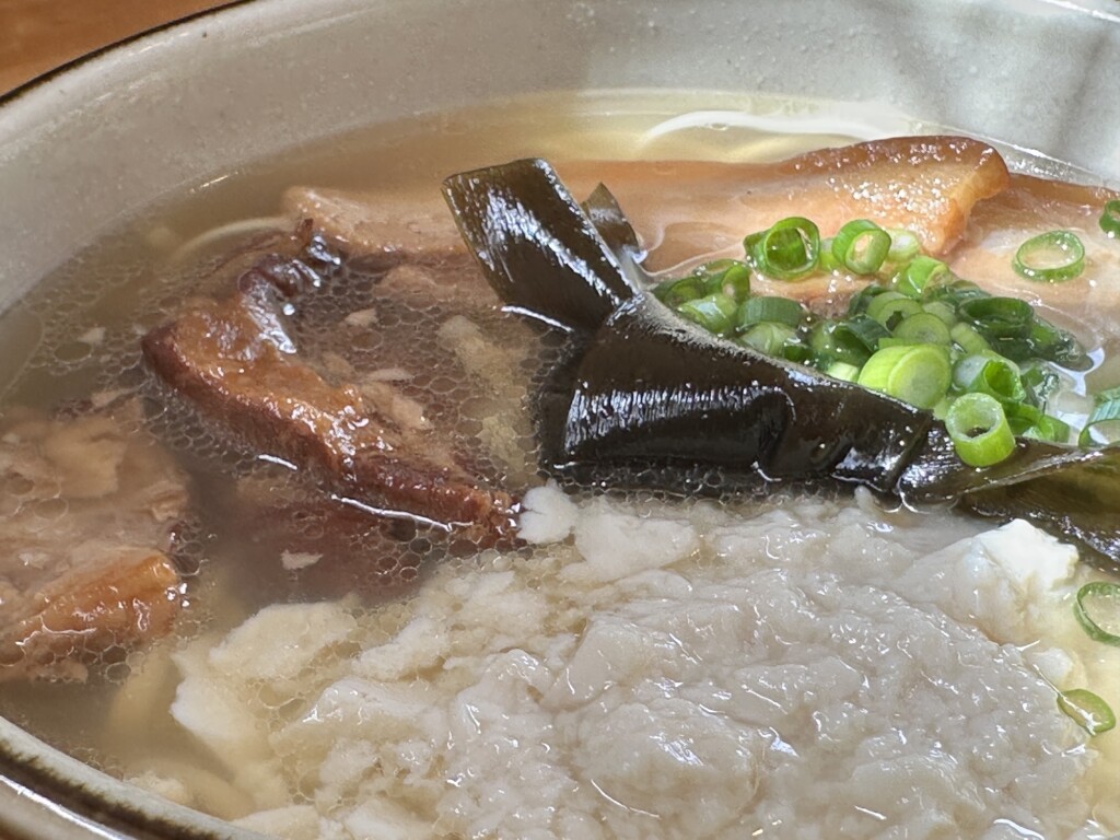 垣花そばの透明なスープ。この黄金色にお豆腐の白とヨモギの緑が映えるんです