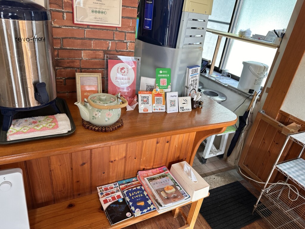 店内のセルフ給茶コーナーと、PayPayなどのQRコード決済が利用可能であることを示す案内板