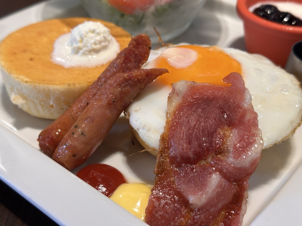 パンケーキに目玉焼きとベーコンを乗せて食べる一口