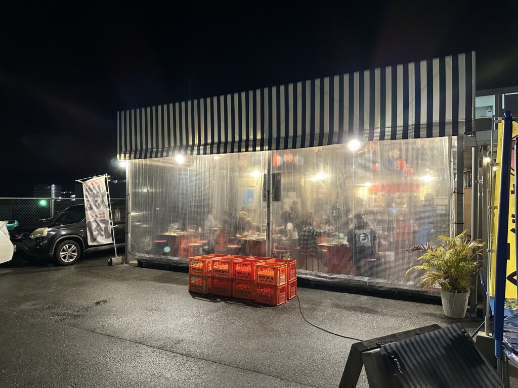 ヤキニクホルモンたなやの夜の外観。ビニールカーテンで囲まれた開放的な雰囲気