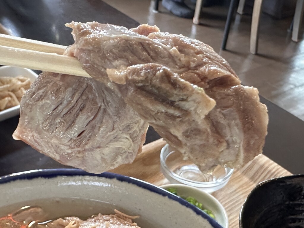 さしきそばの三枚肉を箸で持ち上げた写真