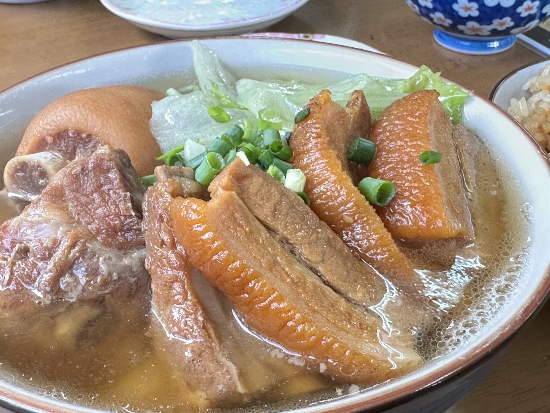 照りのある三枚肉とソーキ、てびち、レタスが盛り付けられたミックスそばのアップ