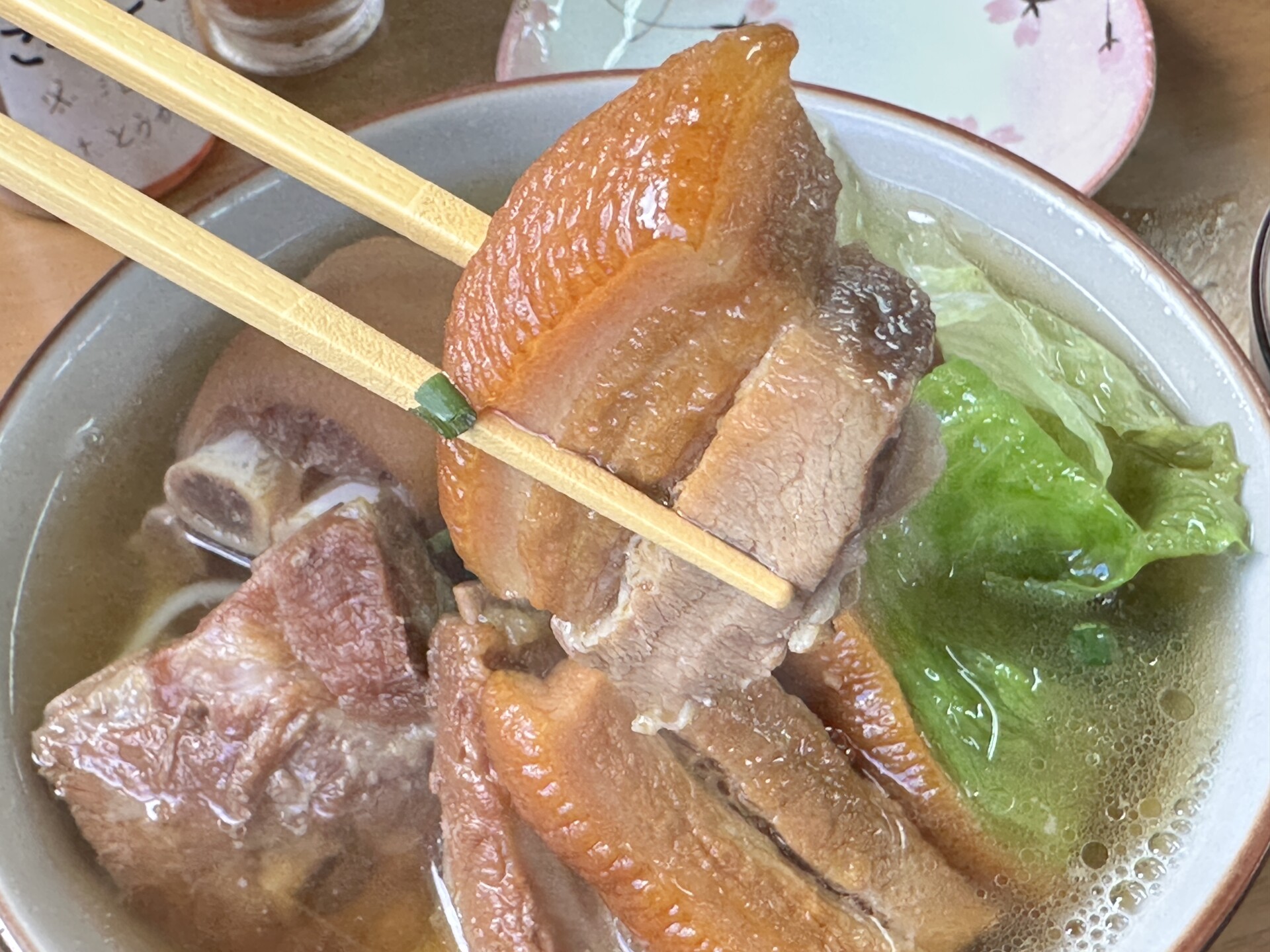 箸で持ち上げた分厚く艶やかな三枚肉